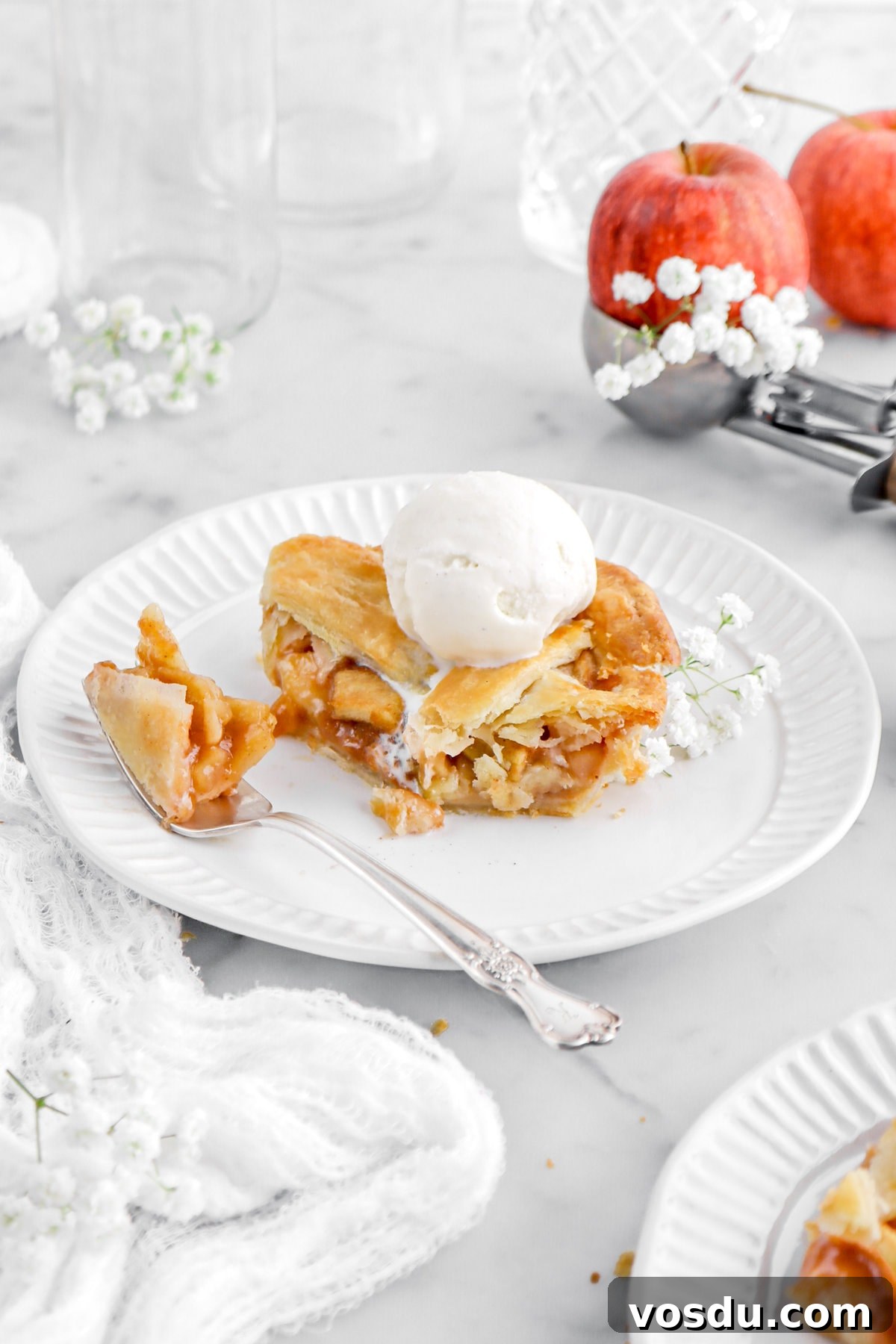 square slice of apple slab pie on plate with forkful of pie beside with white flowers around.