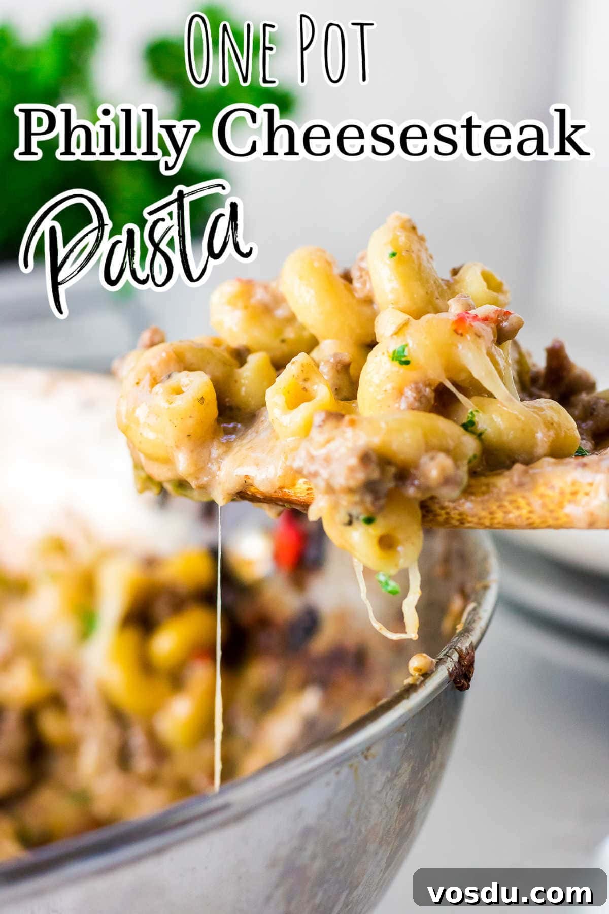One-Pot Philly Cheesesteak Pasta Recipe for Fast Weeknight Dinner 2 A spoonful of pasta being lifted from the pot with strings of cheese falling off it.