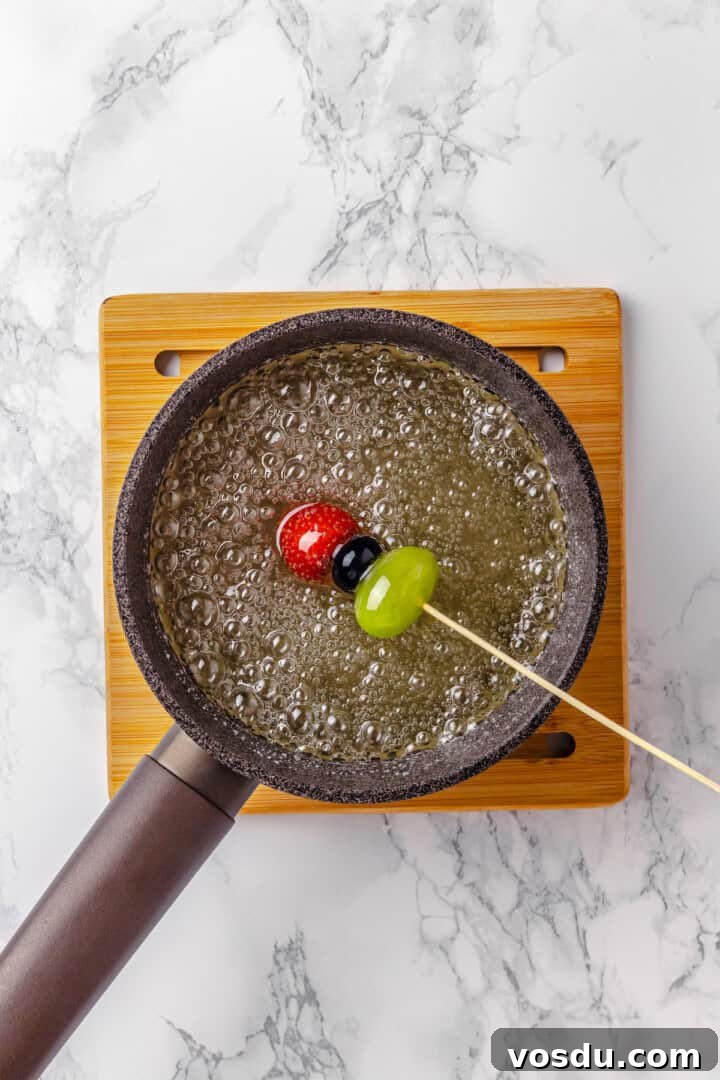 Dipping fruit skewer into sugar mixture Dipping fruit skewer into sugar mixture