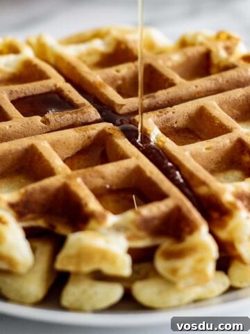 Maple syrup pouring over waffle disk.