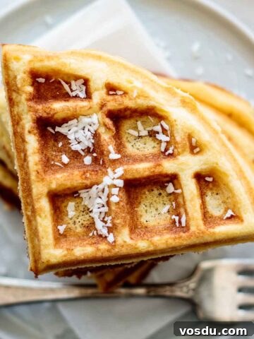 A stack of coconut flour waffles, with coconut flakes on the top.