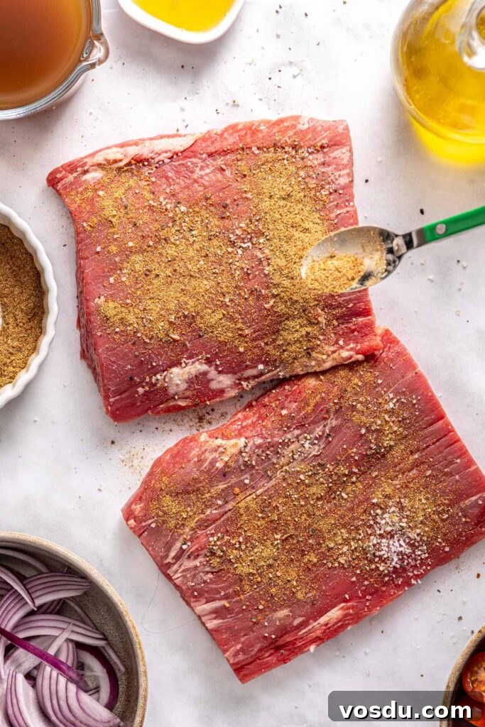 Raw flank steak coated in spices for slow cooker Greek beef bowls
