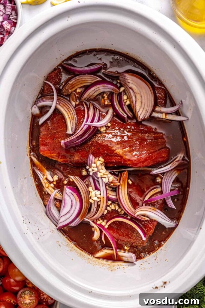 Greek beef bowls ingredients layered in a slow cooker before cooking