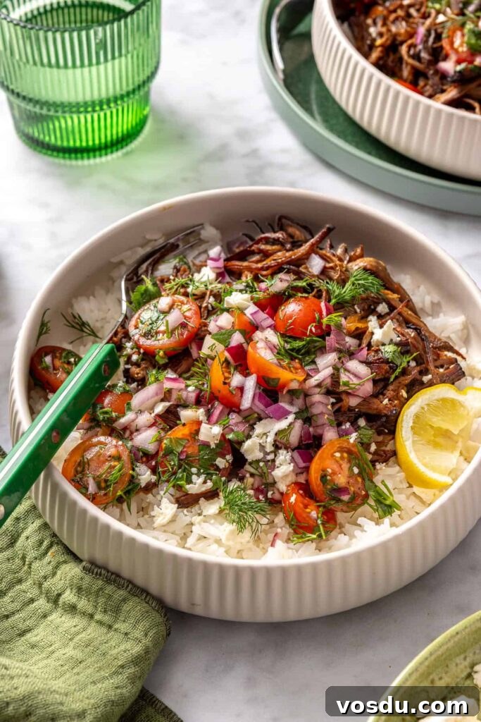 close-up, overhead view of crispy Greek beef bowls with rice, tomato relish, feta, and lemon wedge