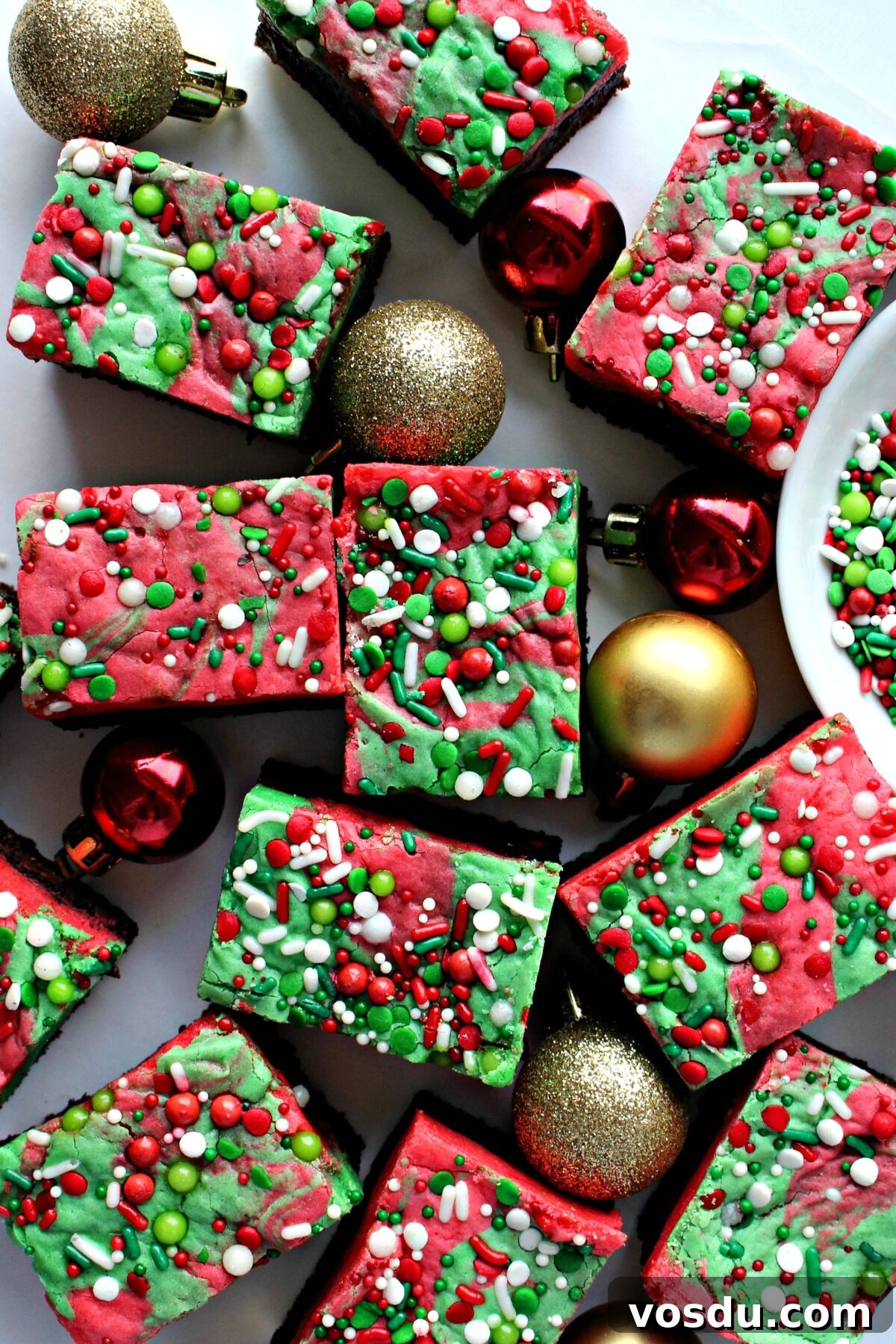 White Chocolate Peppermint Christmas Brownies are a delicious way to usher in the baking season. Christmas colors and winter flavors are swirled into these share-able, mail-able, irresistible treats. (Gluten Free or all-purpose flour recipe) Christmas Brownies with red and green swirled blondie and sprinkles on top.