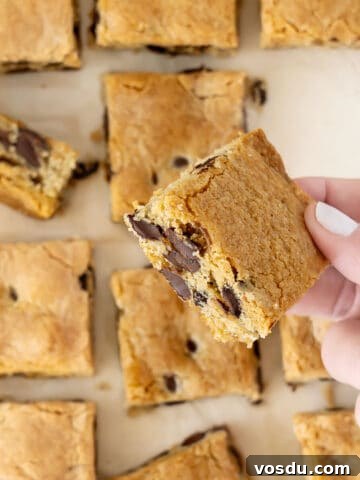 Holding a chocolate chip blondie square. More blondies below.