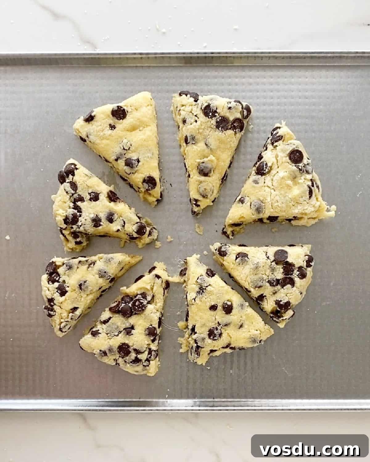 Irresistible Chocolate Chip Scones Recipe for Perfect Breakfast 7 Triangles of chocolate chip scones before baking on a metal baking sheet.