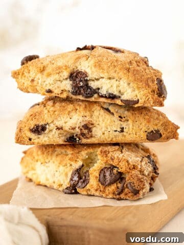 Wooden board with three chocolate chunk cherry scones stacked. White beige background.