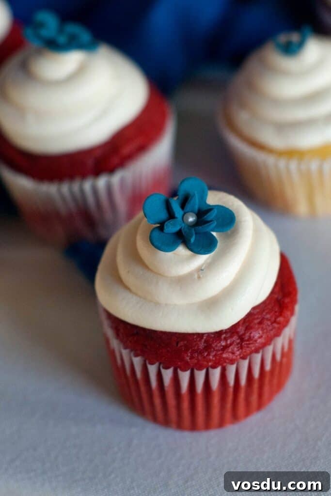 Red Velvet Cupcakes Recipe with Cream Cheese Frosting 2 Two Easy Red Velvet Cupcakes with cream cheese frosting and a blue decorative flower on top.