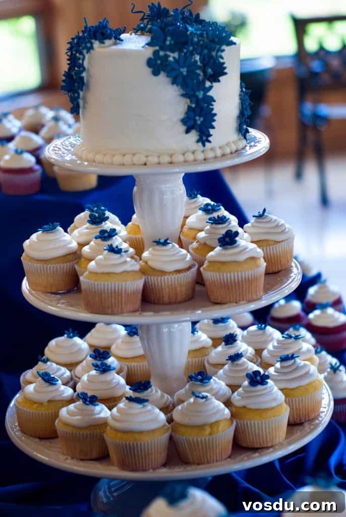 Red Velvet Cupcakes Recipe with Cream Cheese Frosting 3 Delicious cake with white frosting and blue flowers surrounded by white cupcakes.