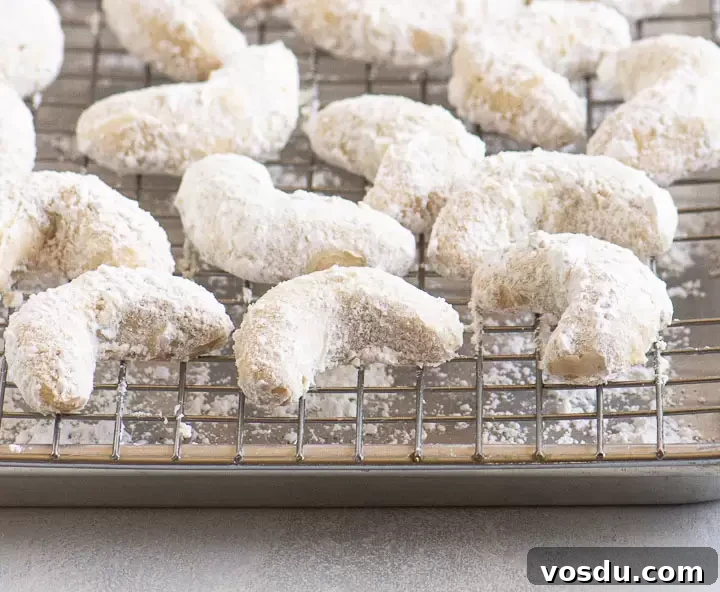 Buttery Almond Crescent Cookies Recipe for Tender, Nutty Crescents 2 cookies on a wire rack set on top of a baking sheet