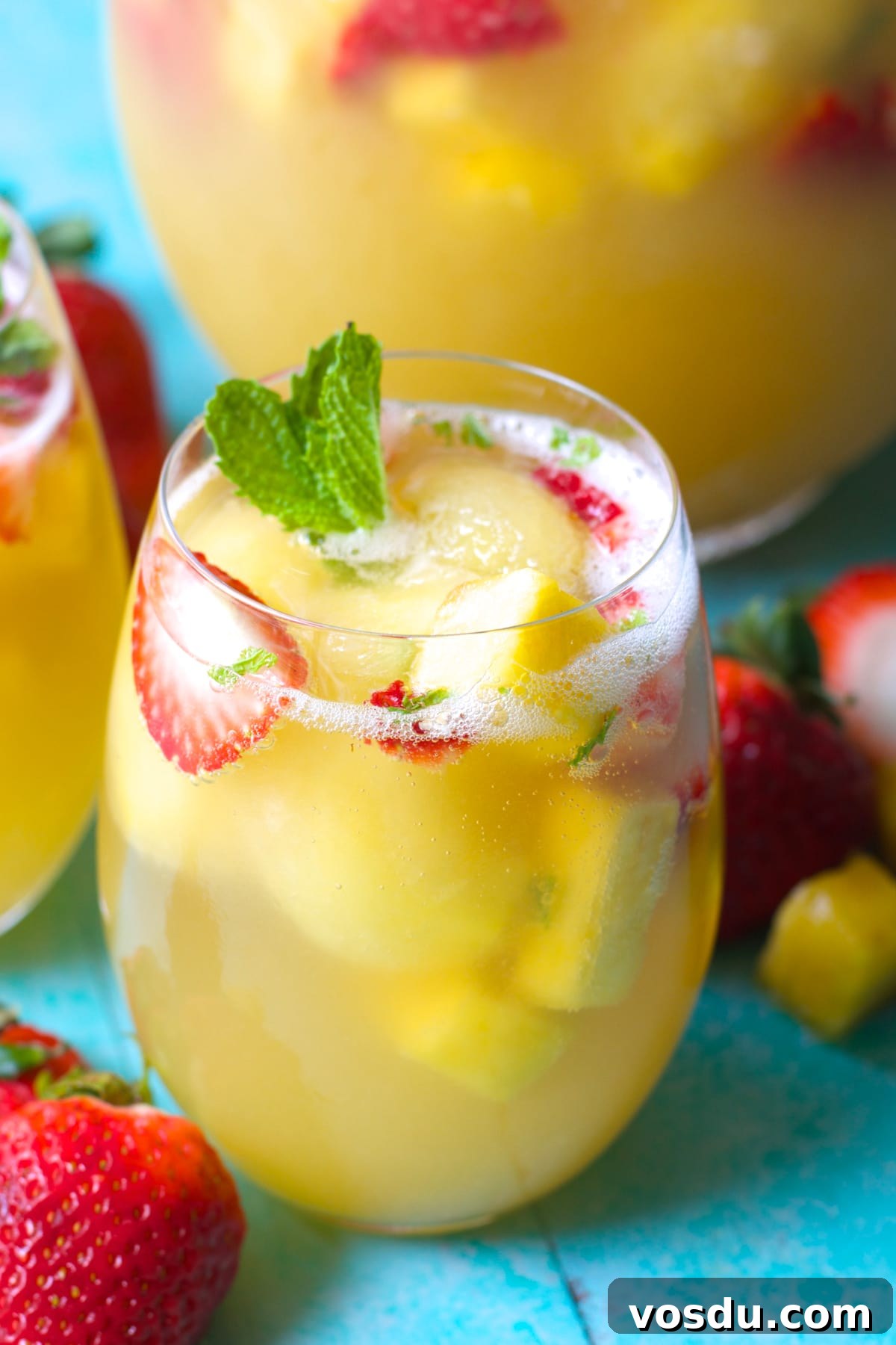 Sparkling Pineapple Punch Recipe with Video Tutorial 2 Close up of a glass of strawberry pineapple punch garnished with mint leaves and fresh fruit.
