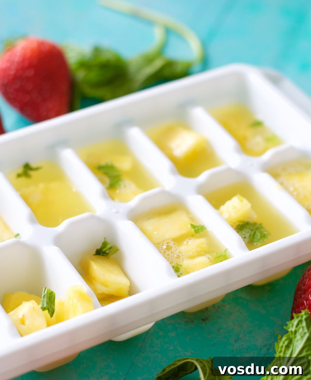 Sparkling Pineapple Punch Recipe with Video Tutorial 4 An ice cube tray filled with ginger ale, fresh pineapple chunks, and mint leaves.