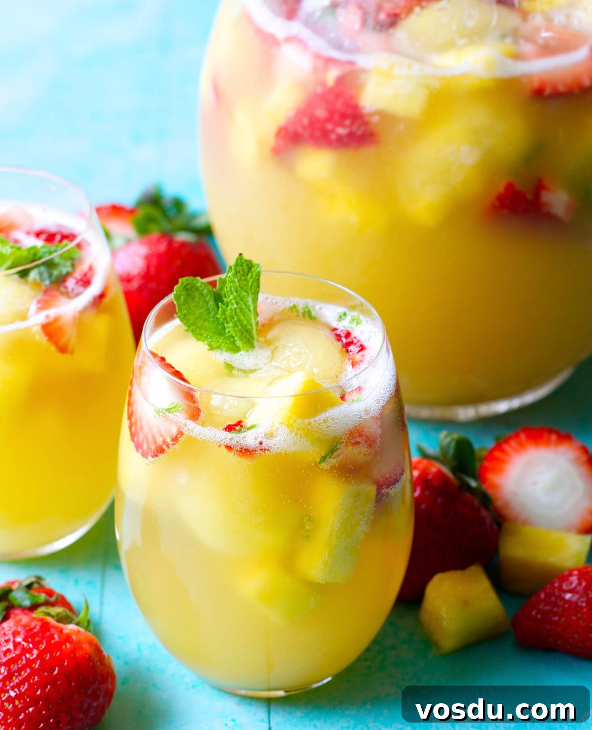 Sparkling Pineapple Punch Recipe with Video Tutorial 5 Two glasses of punch with pineapple juice sitting in front of a pitcher of punch.