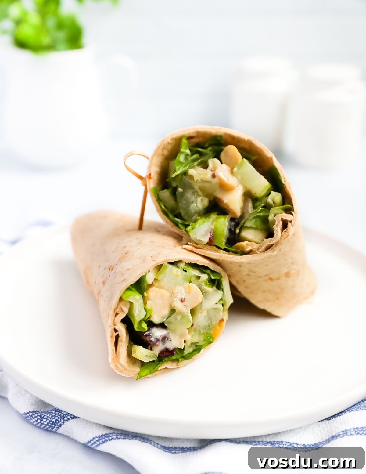 Flavorful Vegan Chickpea Salad with Lemon Herb Dressing 6 A wrap with fresh vegetables inside it on a white plate.