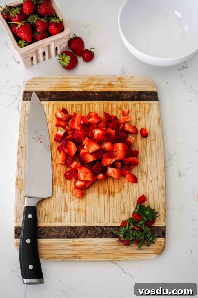 Homemade Small-Batch Strawberry Syrup Recipe 5 Diced strawberries on a wooden cutting board.