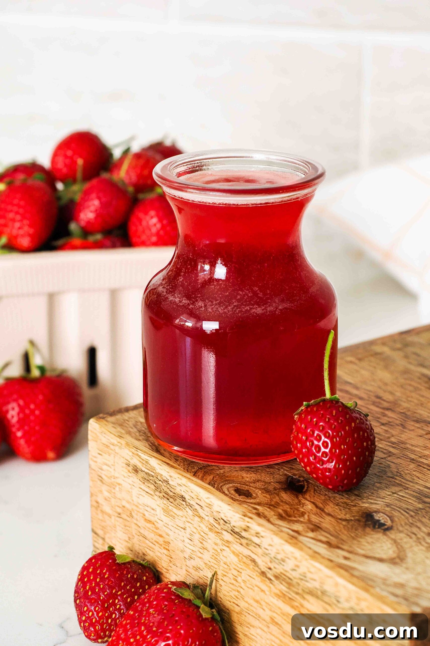 Homemade Small-Batch Strawberry Syrup Recipe 10 A small glass jar of strawberry simple syrup on a wooden platform.
