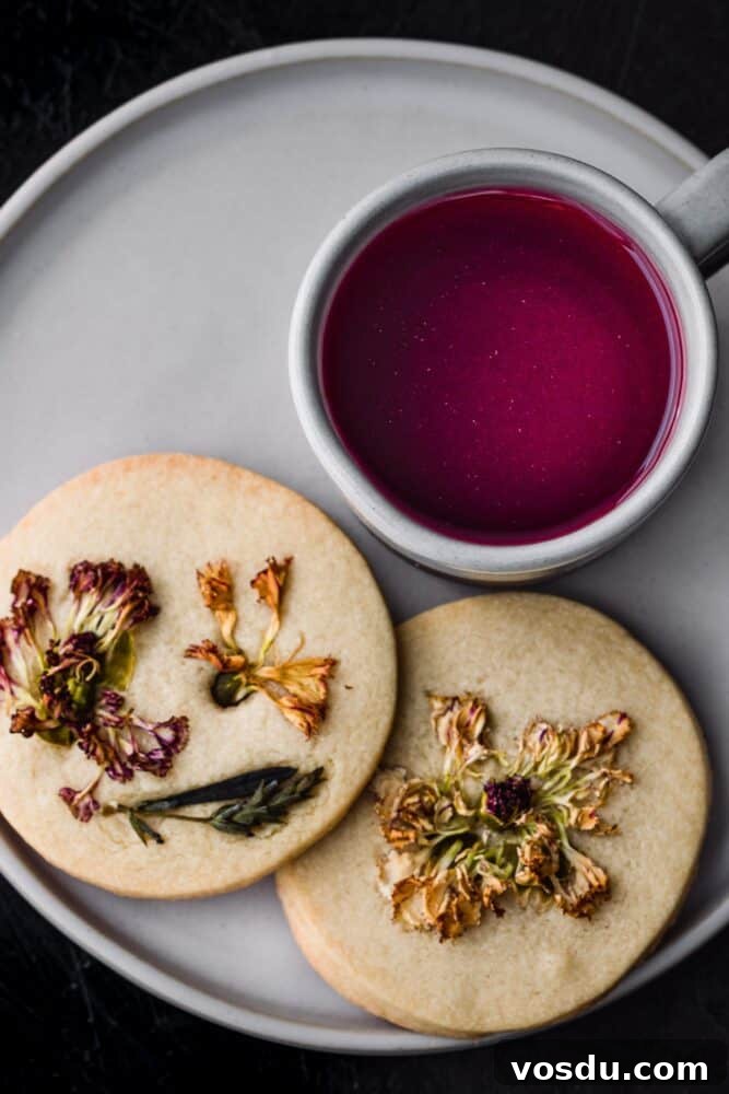 Top San Francisco Coffee Shops for Digital Nomads — 2026 Guide 3 A burgundy tea in a white mug next to two dried edible flower shortbread cookies