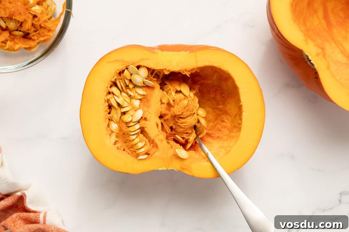 Homemade Pumpkin Puree From Scratch — Step-by-Step Recipe 3 a pie pumpkin cut in half on a baking sheet. A spoon is being used to scrape the seeds out