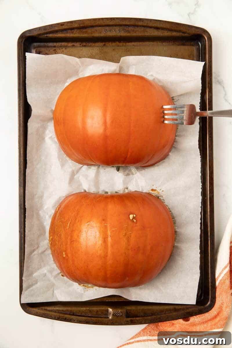 Homemade Pumpkin Puree From Scratch — Step-by-Step Recipe 5 a baked pie pumpkin on a baking sheet with a fork stuck into the flesh