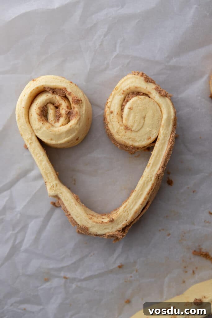Heart-Shaped Cinnamon Rolls for Valentine’s Day Using Canned Dough 5 Unbaked cinnamon roll dough shaped into a heart on parchment paper