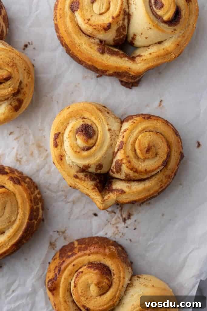 Heart-Shaped Cinnamon Rolls for Valentine’s Day Using Canned Dough 8 Baked heart-shaped cinnamon rolls without frosting on parchment paper