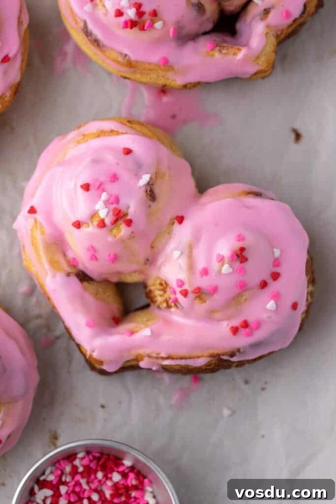 Heart-Shaped Cinnamon Rolls for Valentine’s Day Using Canned Dough 9 Frosted heart-shaped cinnamon rolls with pink icing and Valentine’s sprinkles
