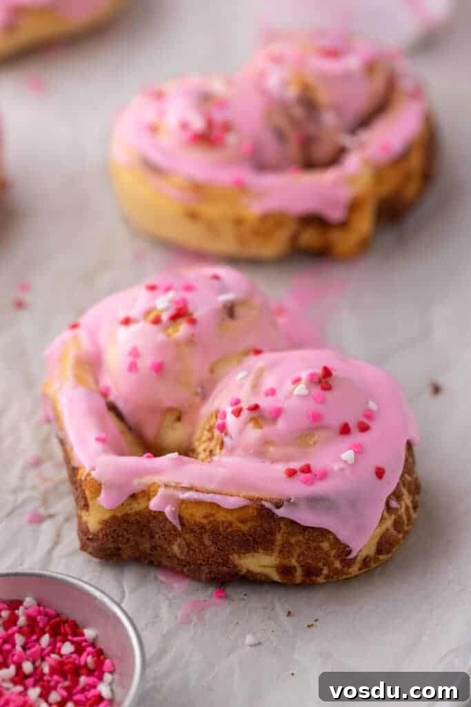 Heart-Shaped Cinnamon Rolls for Valentine’s Day Using Canned Dough 10 Close-up of heart-shaped cinnamon roll with pink frosting and sprinkles