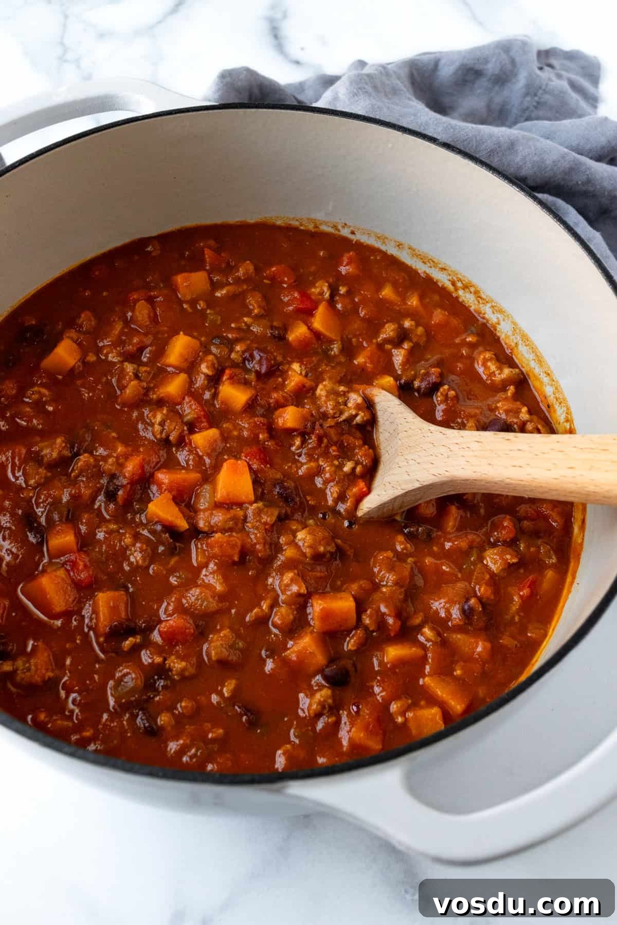 Butternut Squash Chili with Ground Turkey in a Pot with a Wooden Spoon.