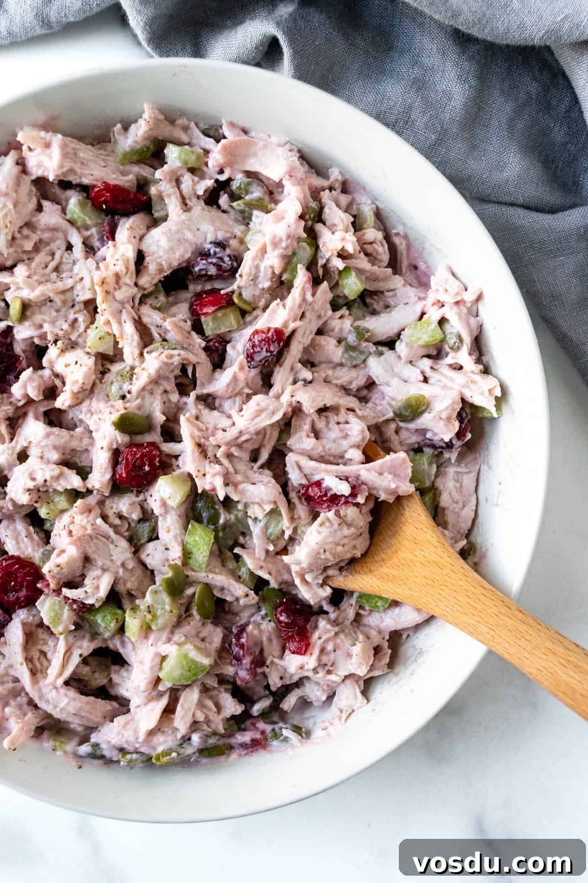 Cranberry Turkey Salad Recipe for Holiday Leftovers 2 Cranberry Turkey Salad in a white bowl with a wooden spoon.