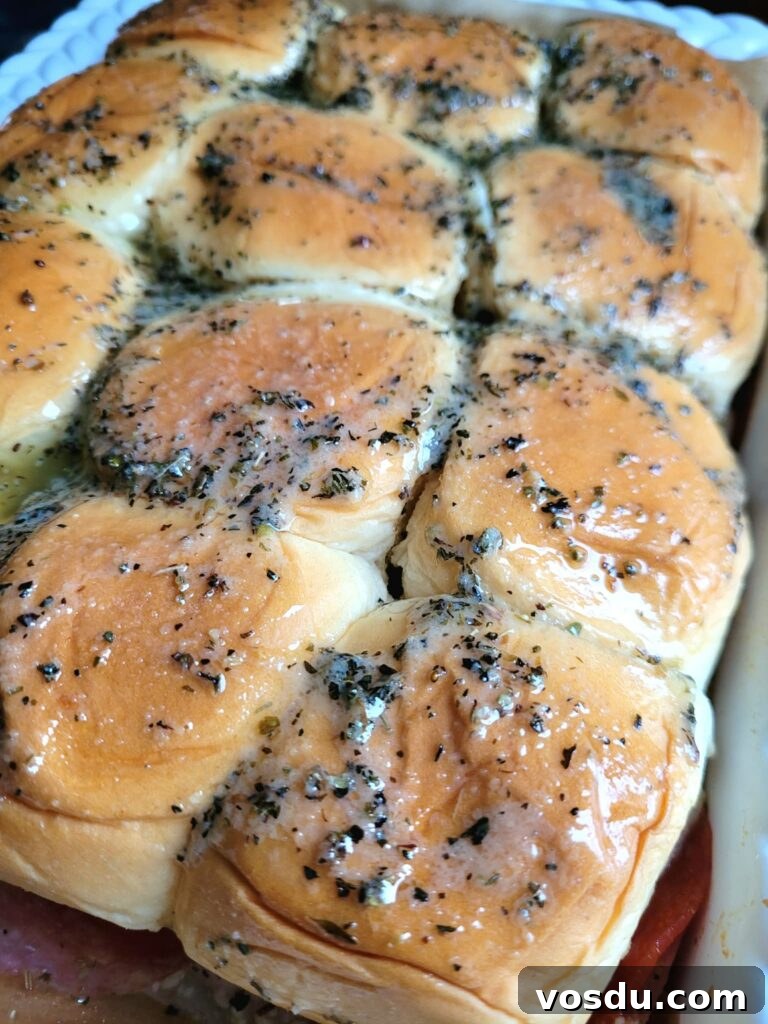Italian Hawaiian Mini Roll Sliders Recipe 8 Drizzling melted butter with oregano, basil, and garlic over Italian ham and cheese sliders before baking.