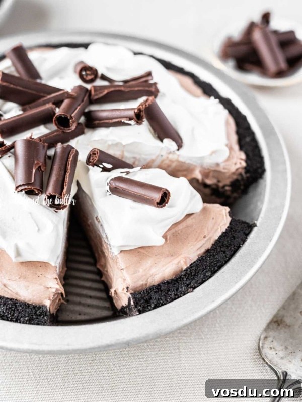 Cookies and Cream Fudge Recipe: Rich No-Bake Dessert Guide 11 Angled image of sliced no-bake chocolate cream pie with chocolate wafer crust and garnished with Cool Whip and chocolate curls.