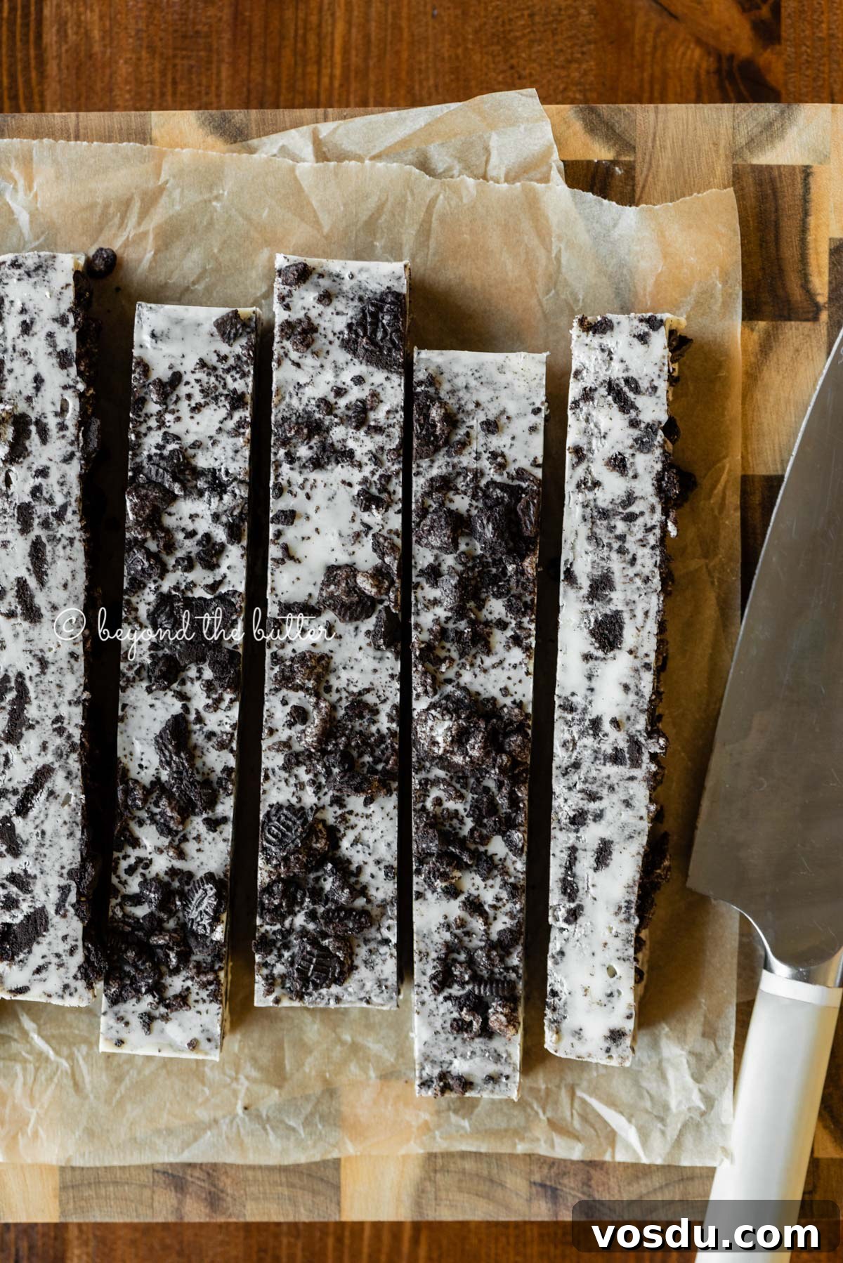 Cookies and Cream Fudge Recipe: Rich No-Bake Dessert Guide 3 Bars of cookies and cream fudge on brown parchment paper and wood cutting board with knife on top | All Images © Beyond the Butter®