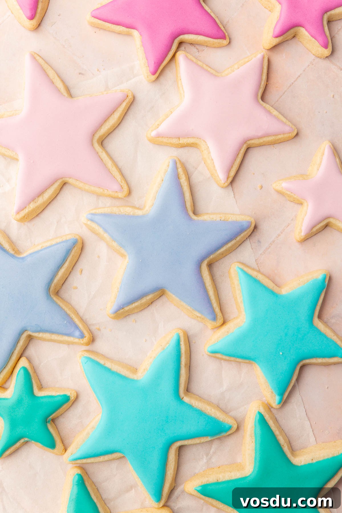 Perfect Royal Icing Recipe: Smooth, Glossy, and Pipe-Ready 11 Star sugar cookies frosted with pink, purple, blue and green royal icing that has dried.