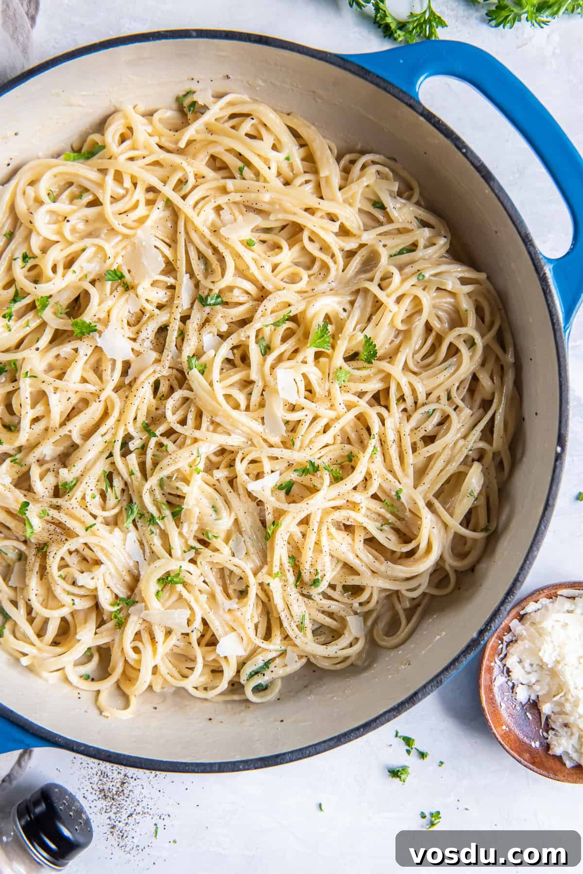 Creamy Parmesan Noodles with Garlic and Herbs 2 Parmesan Noodles in a blue skillet next to a small bowl of Parmesan.