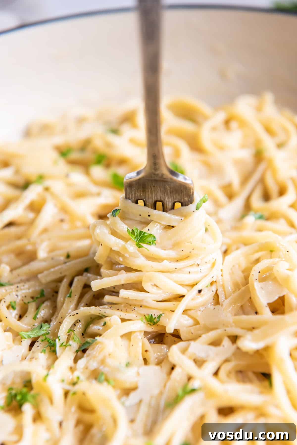 Creamy Parmesan Noodles with Garlic and Herbs 3 A fork twirls cooked linguine in a skillet.