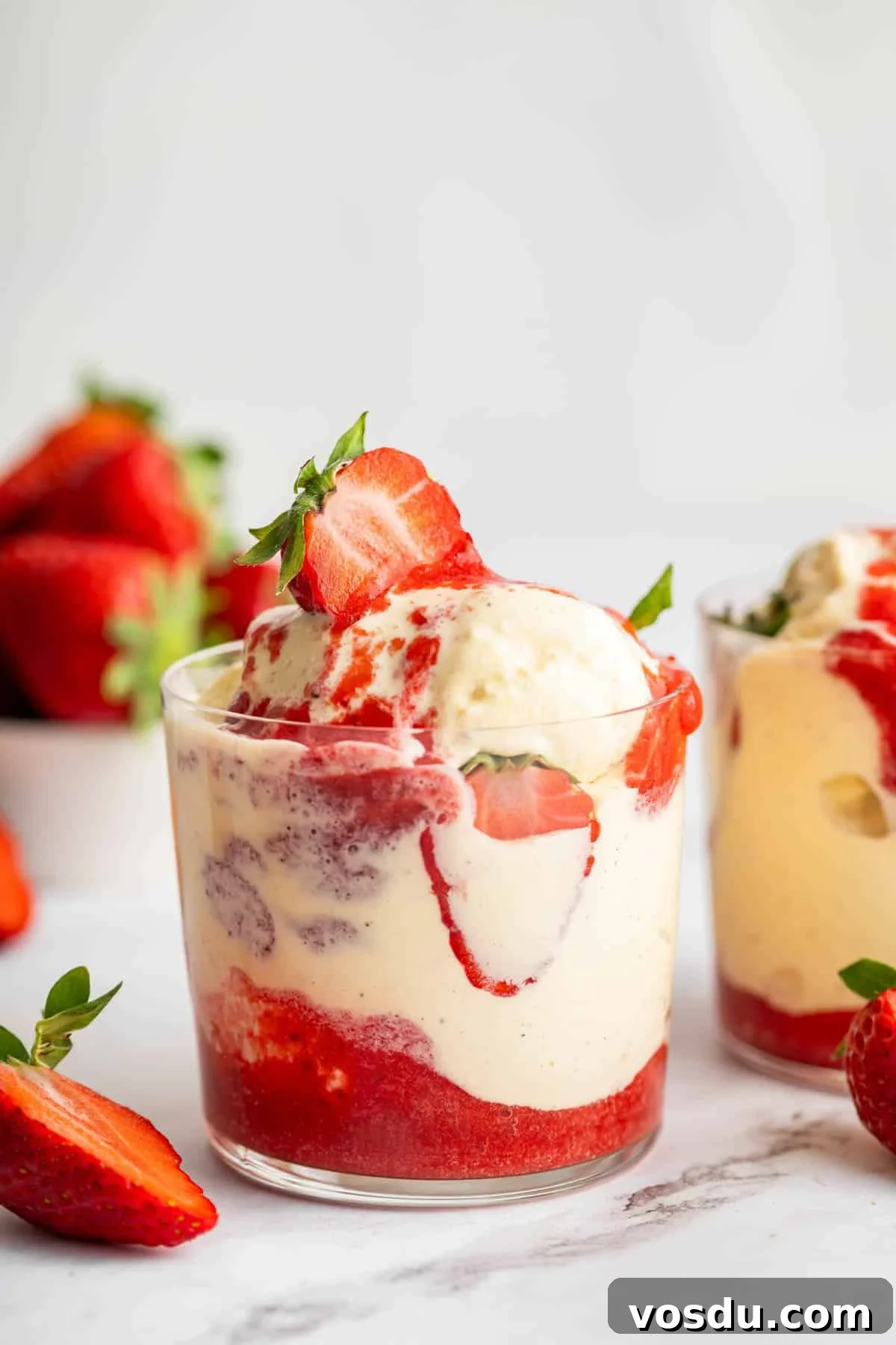 Decadent Homemade Strawberry Sundae Recipe 3 Two glass cups full of vanilla ice cream and fresh strawberry sauce sundae.