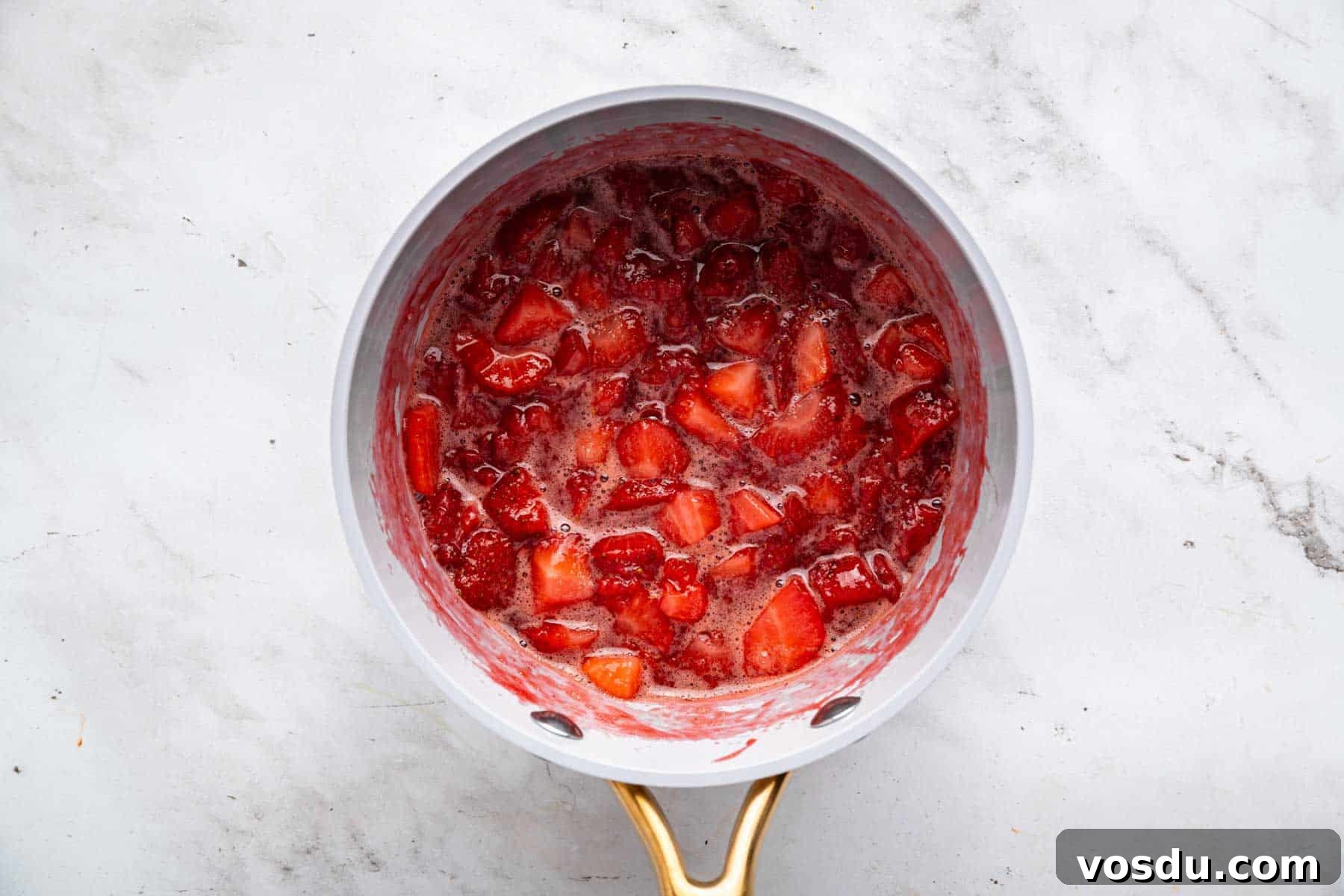 Decadent Homemade Strawberry Sundae Recipe 6 Cooked fruit bubbling in a small grey skillet.