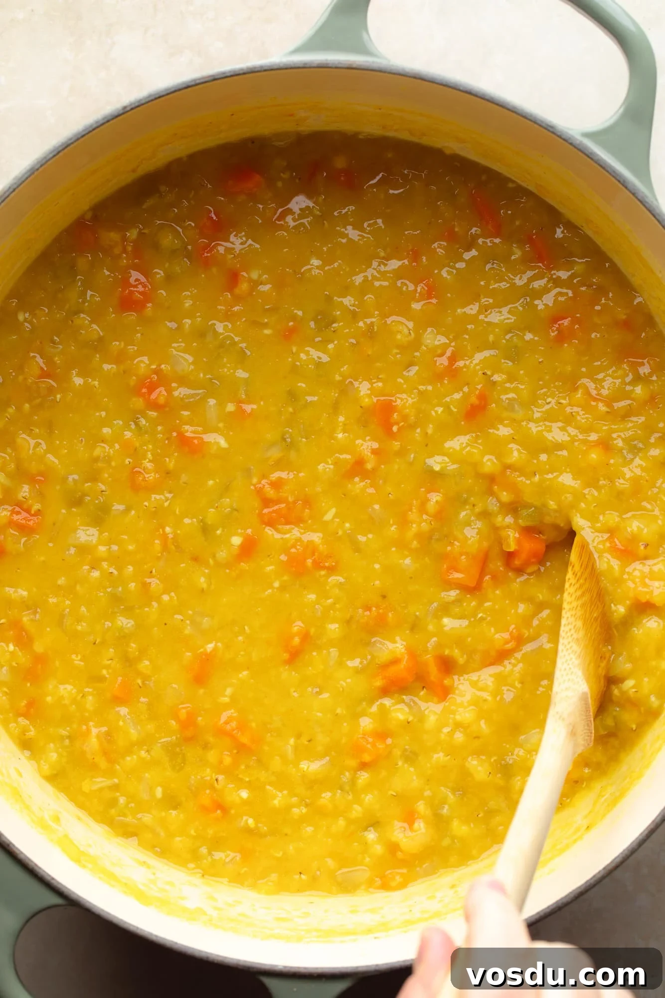 Zesty Lemon Lentil Soup Recipe for Bright, Comforting Meals 5 overhead view of wooden spoon stirring lemon lentil soup in a pot.