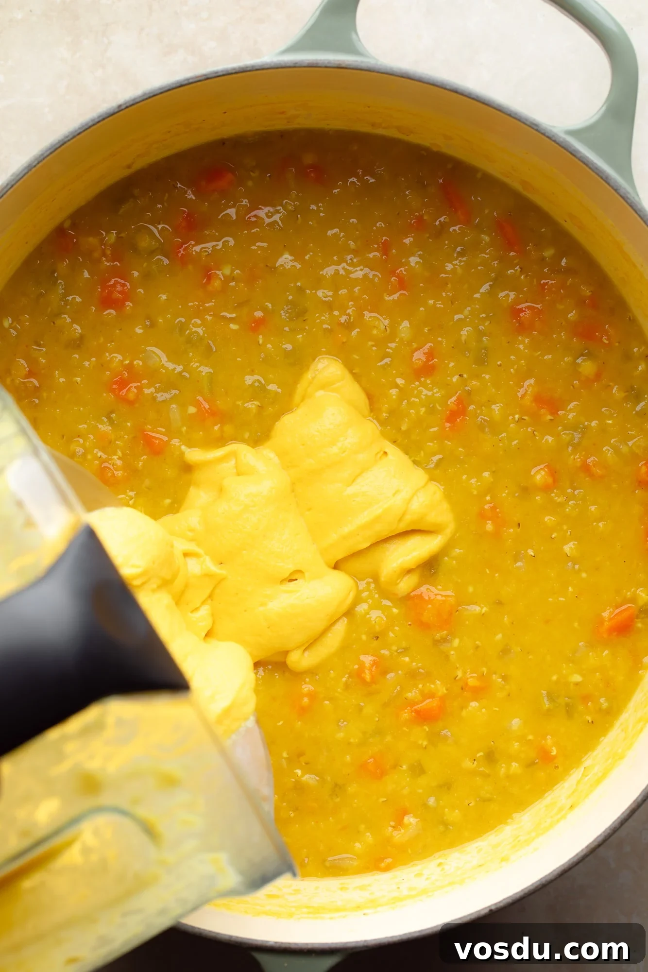 Zesty Lemon Lentil Soup Recipe for Bright, Comforting Meals 6 pouring a creamy yellow mixture into a large pot of lemon lentil soup.