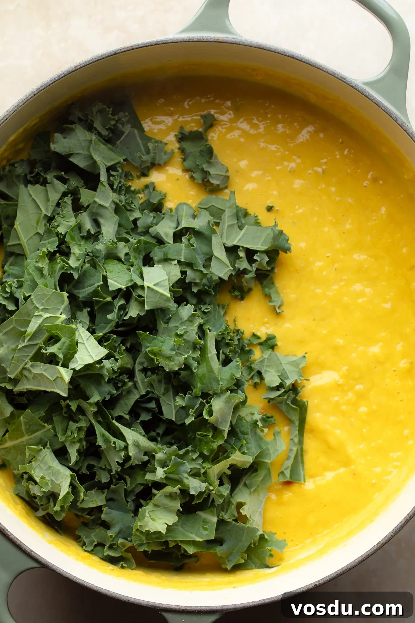 Zesty Lemon Lentil Soup Recipe for Bright, Comforting Meals 7 overhead view of chopped kale on top of lemon lentil soup in a pot.