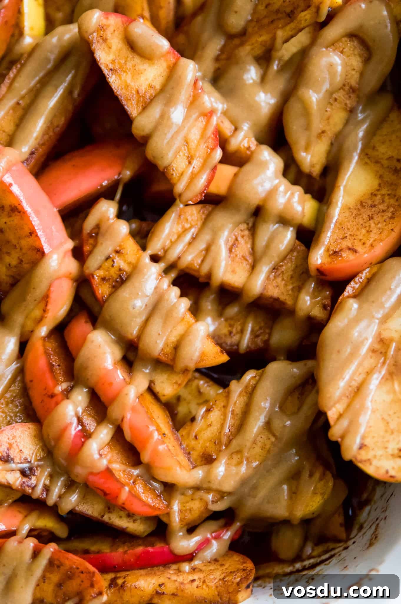 Baked Apple Slices with Homemade Caramel Sauce 2 Baked apple slices in a casserole dish with caramel drizzled on top.