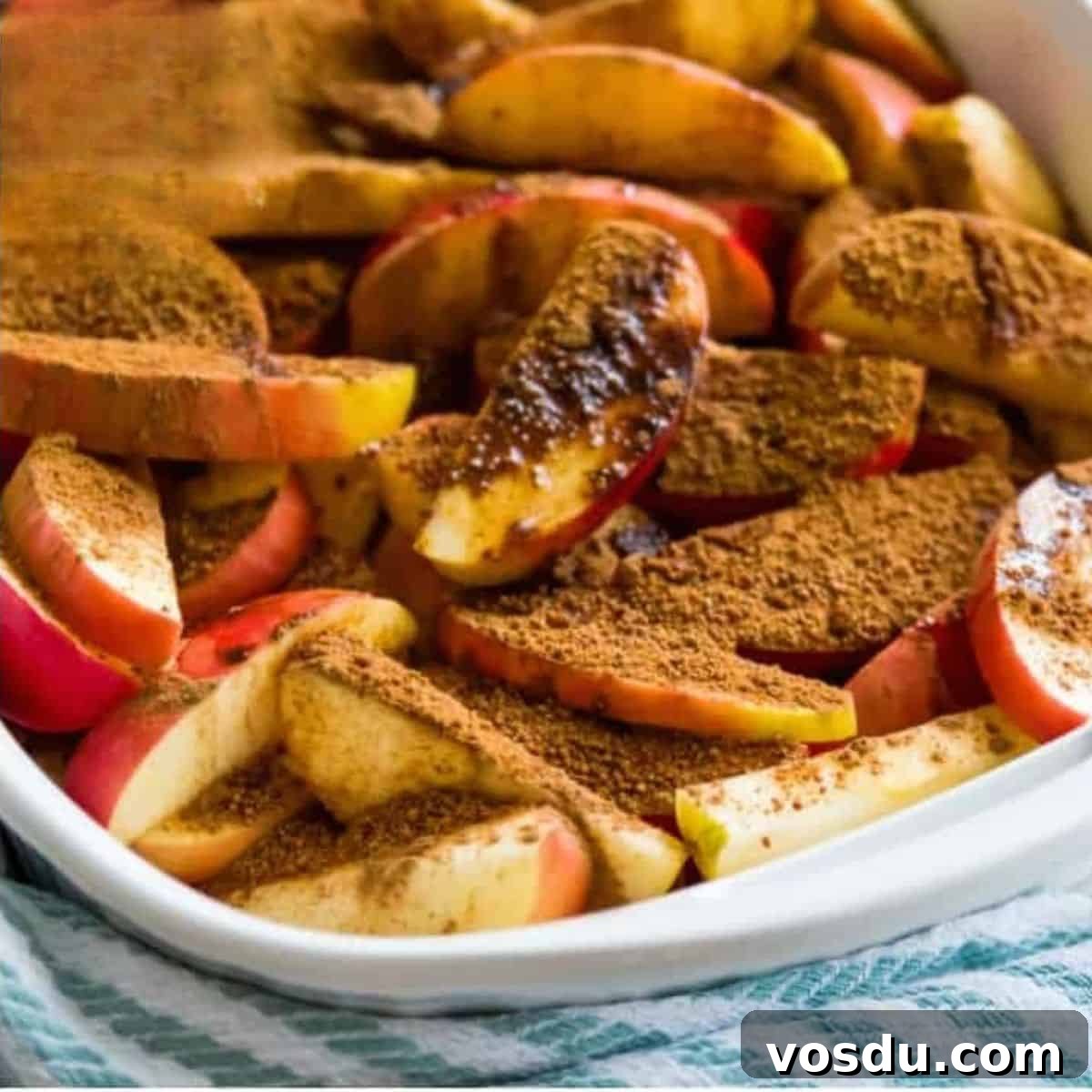 Baked Apple Slices with Homemade Caramel Sauce 5 A casserole dish filled with apple slices coated in a cinnamon sugar mixture.
