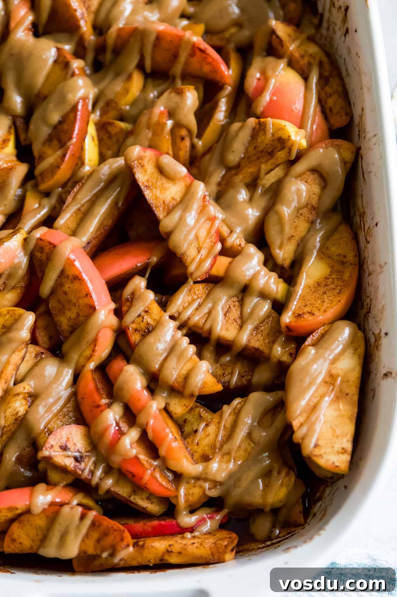 Baked Apple Slices with Homemade Caramel Sauce 10 A casserole dish full of baked apple slices drizzled in caramel.