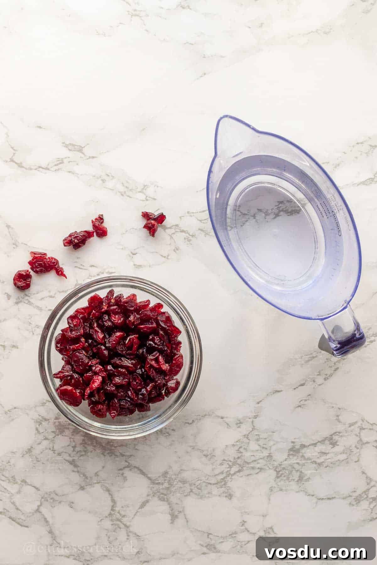 Cranberry Chicken Salad with Toasted Pecans and Citrus Vinaigrette 4 Glass bowl of cranberries and water on marble countertop.
