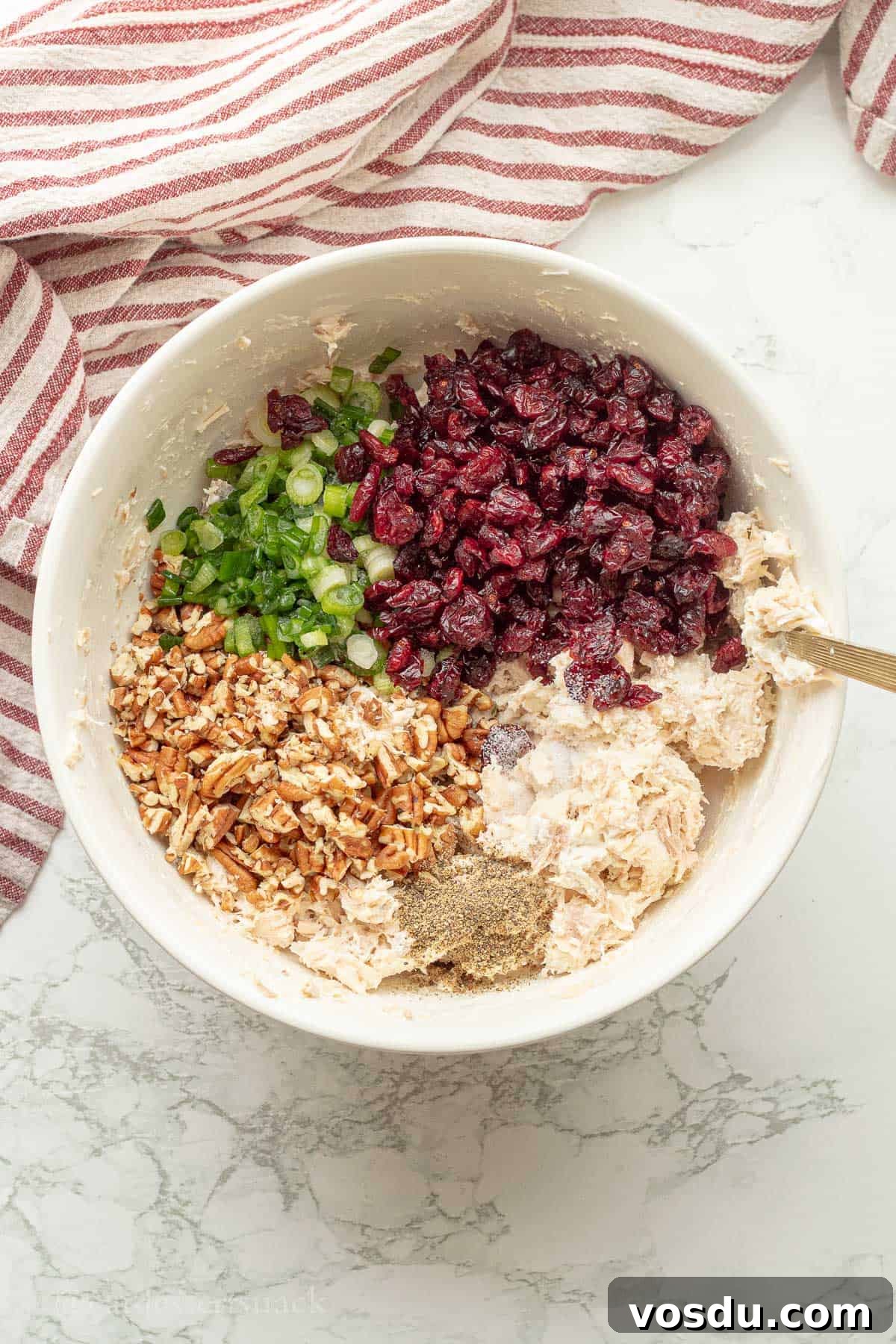 Cranberry Chicken Salad with Toasted Pecans and Citrus Vinaigrette 6 Ingredients for chicken cranberry salad in white bowl with gold spoon.