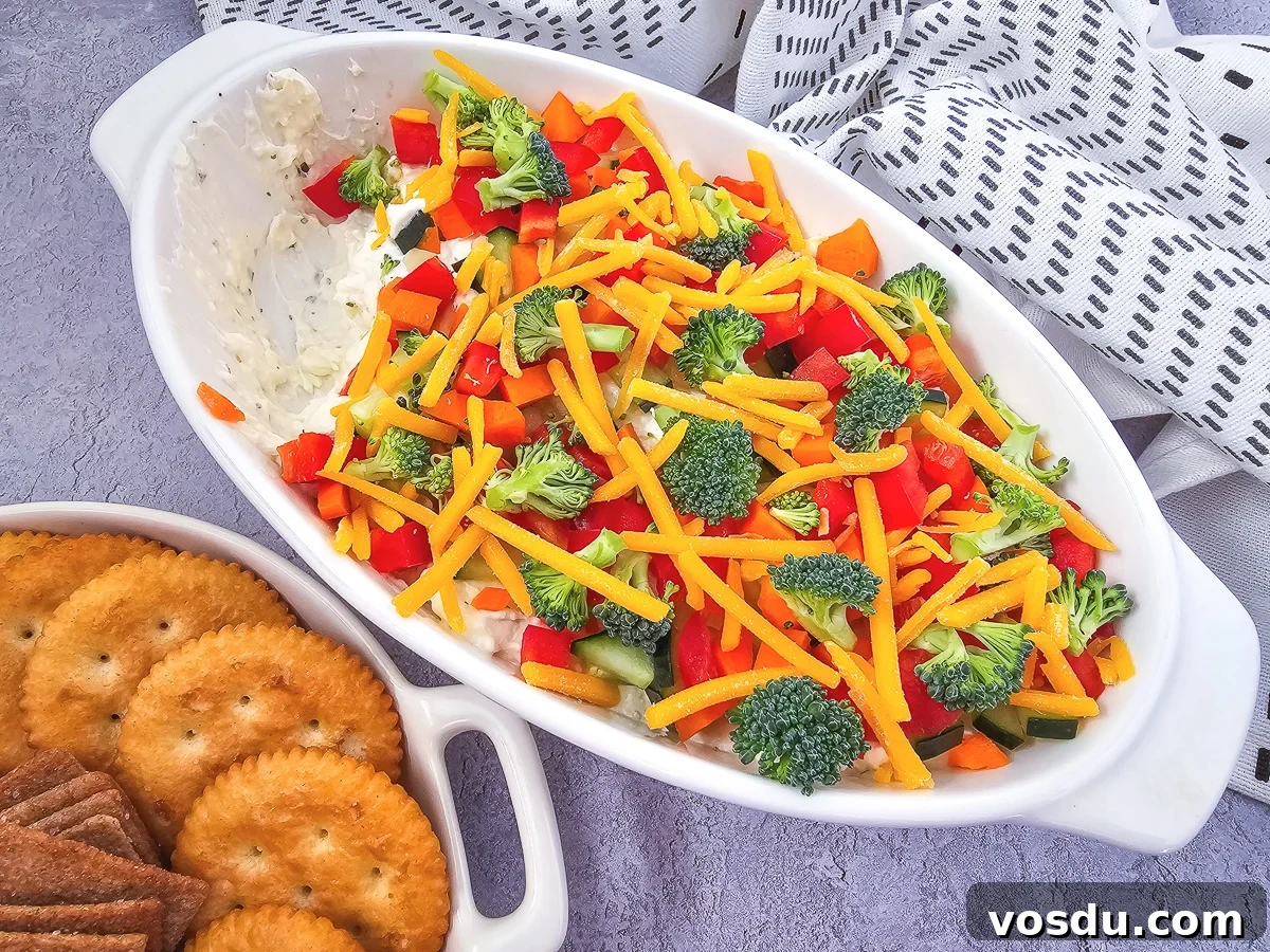 Overhead view of veggie pizza dip in a white bowl.