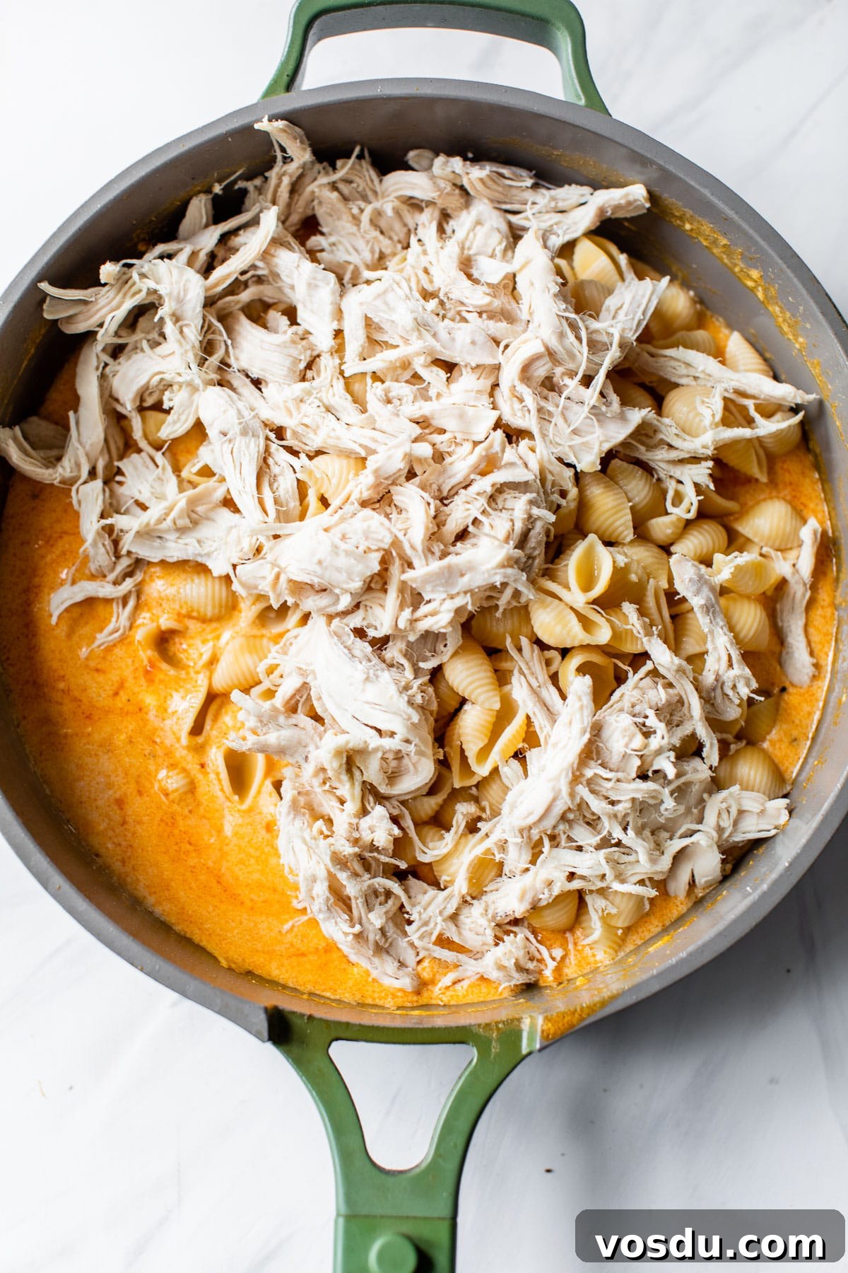 Creamy Buffalo Chicken Pasta Recipe with Tangy Wing Sauce 5 shredded cooked chicken and cooked pasta in a skillet with buffalo sauce