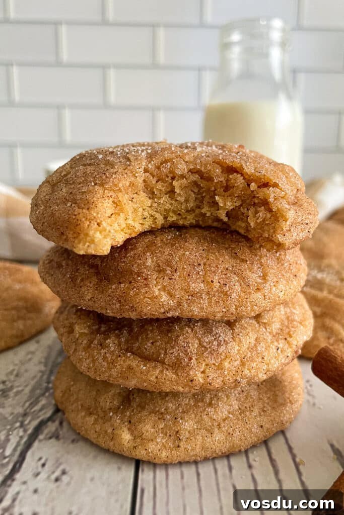 Best Pumpkin snickerdoodle cookie recipe with 4 cookies stacked on top of each other.  The top cookie has a bite taken out of it. 