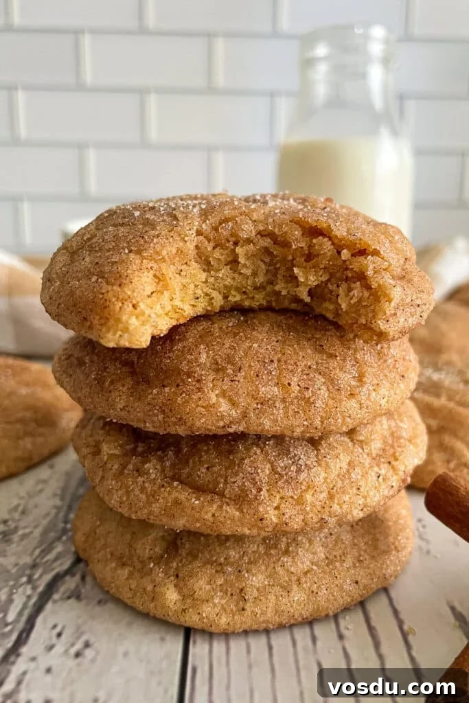 Best Pumpkin snickerdoodle cookie recipe with 4 cookies stacked on top of each other. The top cookie has a bite taken out of it.